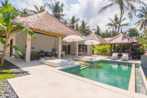 a villa with a swimming pool and umbrellas at Villa Hidden Pearl, with private cook and pool in Karangasem