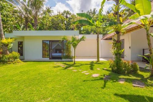 a garden view of a house with palm trees at Villa Hidden Pearl, with private cook and pool in Karangasem