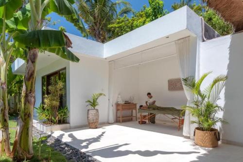 a white house with plants and a person sitting on a desk at Villa Hidden Pearl, with private cook and pool in Karangasem