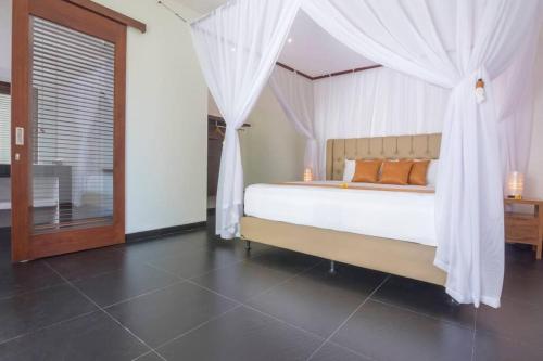 a bedroom with a bed with white drapes at Villa Hidden Pearl, with private cook and pool in Karangasem