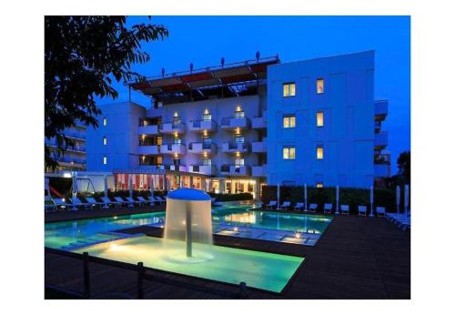 a hotel with a swimming pool in front of a building at Domino Suite Hotel & Residence in Lido di Jesolo