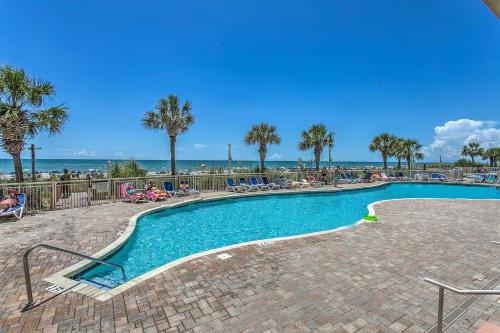 a swimming pool with palm trees and the ocean in the background at Steps to Beach Bay Watch Resort Studio in Myrtle Beach