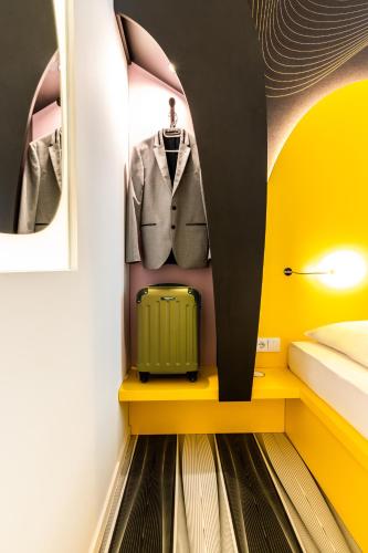 a room with a suit and a suitcase on a shelf at Prize by Radisson, Bonn City in Bonn