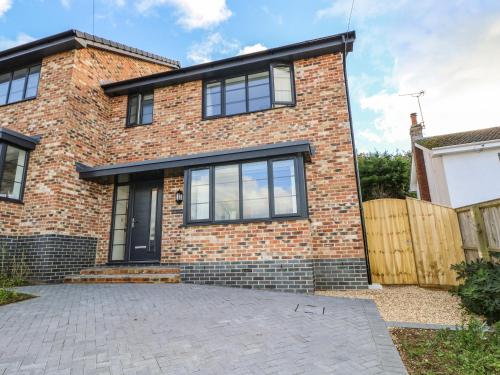 a brick house with black windows and a driveway at Larch Lodge in Totland