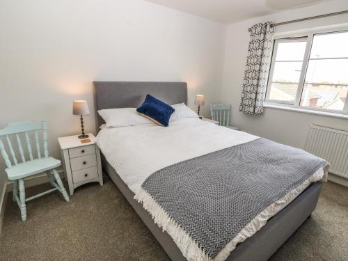 a bedroom with a bed and a chair and a window at Larch Lodge in Totland