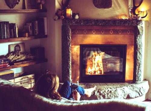 a woman sitting on a couch in front of a fireplace at Maso Azzurro Chalet in Stenico