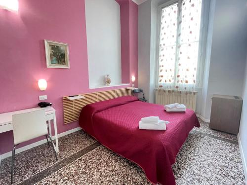 a pink bedroom with a bed with two towels on it at Hotel Serena in Arenzano
