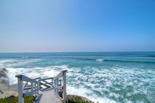 a wooden boardwalk leading to the ocean with waves at Oceanfront Villa with Private Beach Access, Remodeled Kitchen in Carlsbad