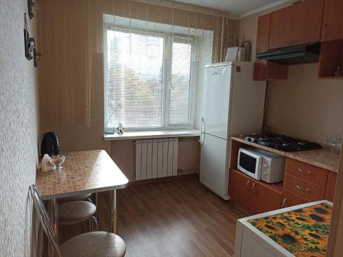 a small kitchen with a white refrigerator and a table at Cozy apartments in the city center Kharkovskaya street in Sumy