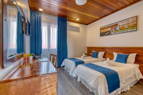 two beds in a hotel room with blue curtains at Swans Cay Hotel in Bocas del Toro
