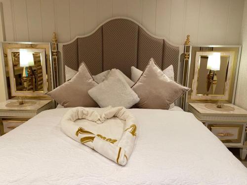 Una cama blanca con una toalla en forma de corazón. en Royal Whirlpool Suites Lüneburger Heide en Rehlingen