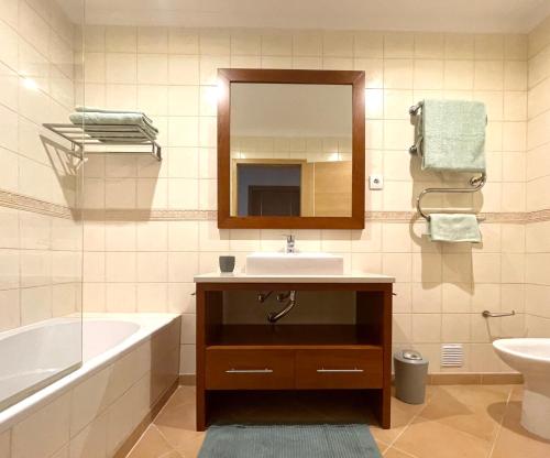 a bathroom with a sink and a tub and a mirror at Muralha Residence in Lagos