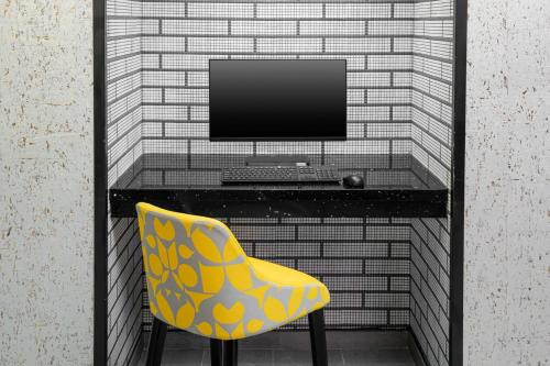 a desk with a computer and a yellow chair at voco Times Square South New York by IHG in New York