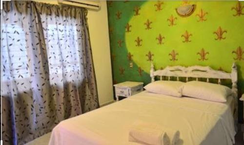 1 dormitorio con cama blanca y pared verde en D'maro hotel, en Playa del Carmen