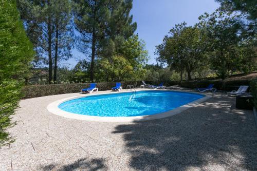 a swimming pool with two blue chairs in a yard at Tapadinho Nature and Pool - Countryside Villa in Castelo de Paiva
