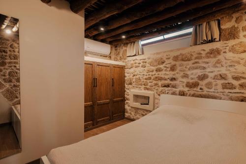 sypialnia z łóżkiem i kamienną ścianą w obiekcie La casa dell'arch w mieście Charaki