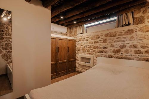 a bedroom with a bed and a stone wall at La casa dell'arch in Haraki
