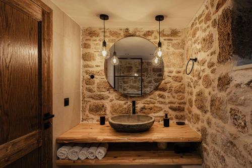 Baño de piedra con lavabo y espejo en La casa dell'arch en Haraki