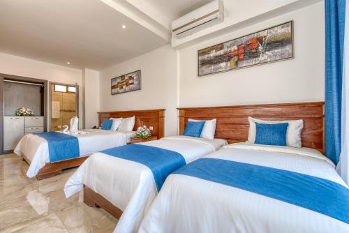 a bedroom with three beds with blue and white sheets at Swans Cay Hotel in Bocas del Toro