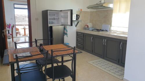 a kitchen with a refrigerator and a table and chairs at CHEZ JOHNNY in Grand Baie