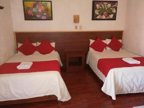 2 camas en una habitación con sábanas rojas y blancas en Hotel Colonial, en Morelia