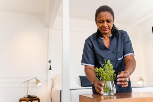 une femme debout à une table avec un vase de fleurs dans l'établissement Grand Hotel Urban, à Antananarivo
