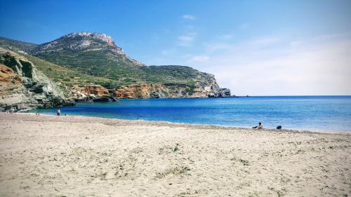 una playa con gente sentada en la arena y el agua en Perigiali Rooms & Apartments Folegandros, en Agali