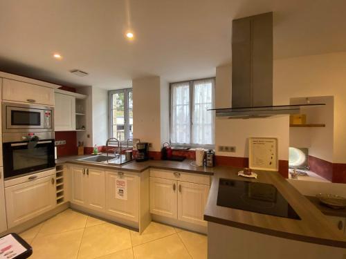 uma cozinha com armários brancos e um forno com placa de fogão em Cottage de charme classé 3 Etoiles - 8 min CNPE Civaux em Gouex
