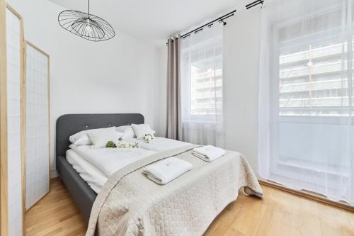 a bedroom with a bed with white sheets and a window at Apartments Wrocław Bajana by Renters in Wrocław