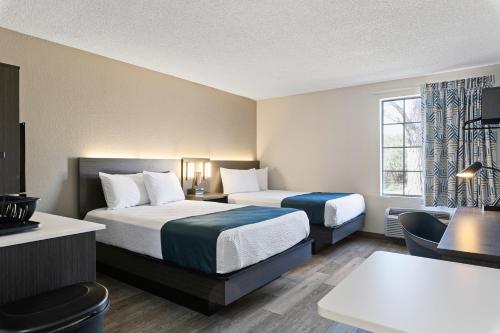 a hotel room with two beds and a desk at Studio 6 Tucson, AZ - North in Tucson