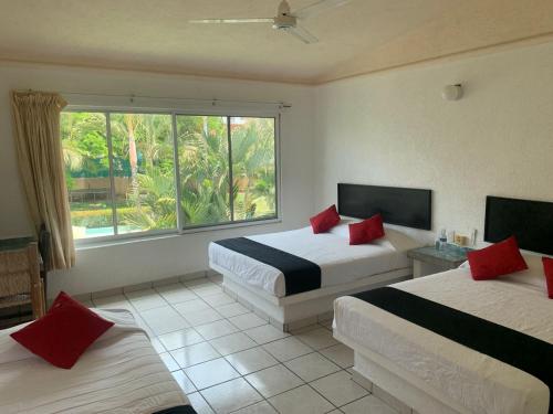 Habitación de hotel con 2 camas y ventana en Hotel Parotas Manzanillo, en Manzanillo