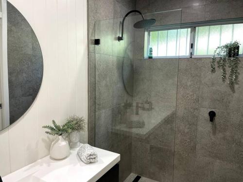 a bathroom with a shower and a sink and a mirror at Kiama Palms on Terralong in Kiama