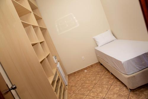 a small room with a bed and shelves at Pousada Costa Rielli in Águas de Lindóia