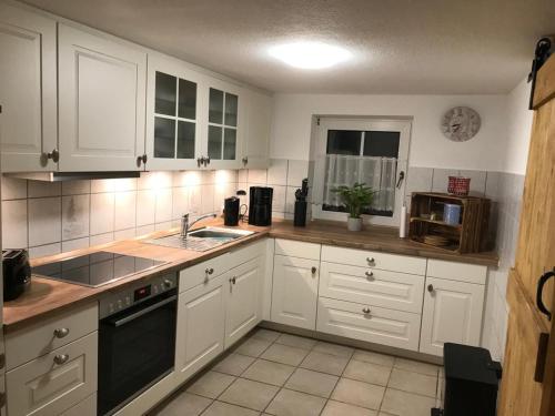 a kitchen with white cabinets and a black appliance at Dat ole Diekhus in Neuendorf-Sachsenbande