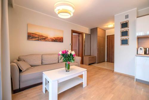- un salon avec un canapé et une table fleurie dans l'établissement Apartament Flores 3 Rezydencja Park Rodzinna - Mielno, à Mielno