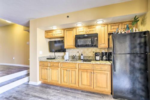 a kitchen with wooden cabinets and a black refrigerator at Beachfront Resort Condo with Lazy River and Pools! in Myrtle Beach