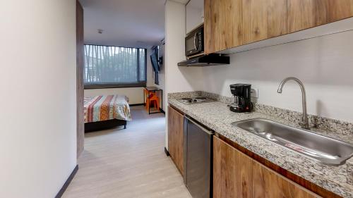 eine Küche mit einem Waschbecken und ein Zimmer mit einem Bett in der Unterkunft Terrazas in Bogotá