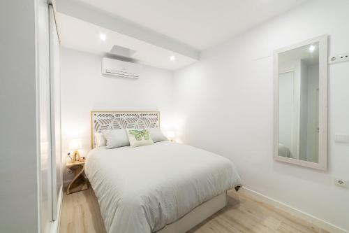 a white bedroom with a bed and a mirror at Loft en el corazón de Cádiz con opción a Parking in Cádiz