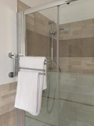 een badkamer met een glazen douche en een handdoek bij Domus Alice in Monserrato