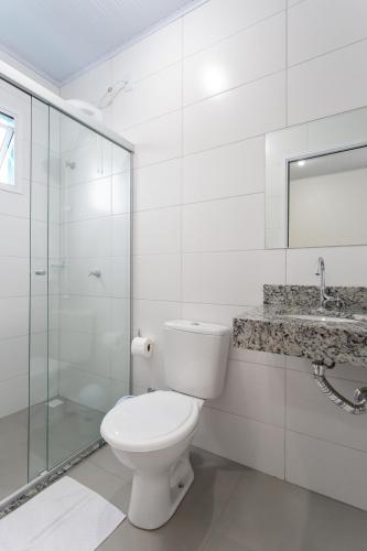a white bathroom with a toilet and a sink at Galileia flat in Santa Maria