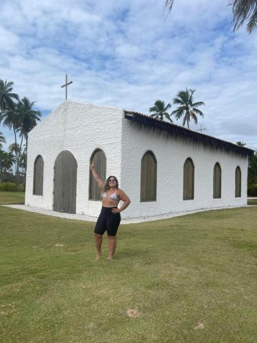 a woman standing in front of a church at Chalé Palhano Beach in São Miguel dos Milagres