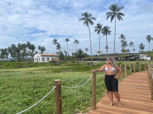 a woman in a bikini standing on a wooden boardwalk at Chalé Palhano Beach in São Miguel dos Milagres