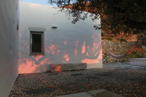 a white building with a window and a wall at Paros Apartments Cottage in Parikia