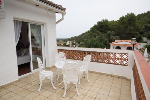 a patio with white chairs and tables on a balcony at El Cid Country Club in Benidoleig