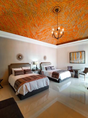two beds in a bedroom with an orange ceiling at Hotel Plaza Cuatro Ciénegas in Cuatrociénegas de Carranza