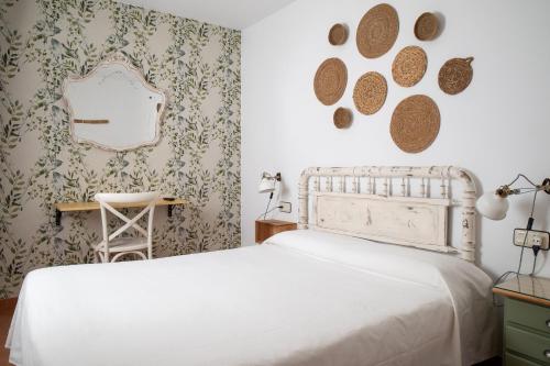 1 dormitorio con cama blanca y espejo en Hostal El Pozo en Chulilla
