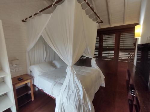 a bedroom with a white bed with a canopy at Monkey Casa Hotel in Trancoso