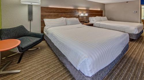 a hotel room with two beds and a chair at Holiday Inn Express Memphis Medical Center - Midtown by IHG in Memphis