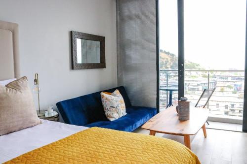 a bedroom with a bed and a blue couch at 2218 at 16 on Bree in Cape Town