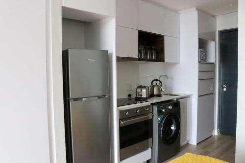 a kitchen with a refrigerator and a washing machine at 2218 at 16 on Bree in Cape Town